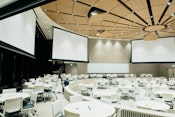 Conference room expertly arranged by event management, featuring sleek screens, organized tables, and comfortable chairs.