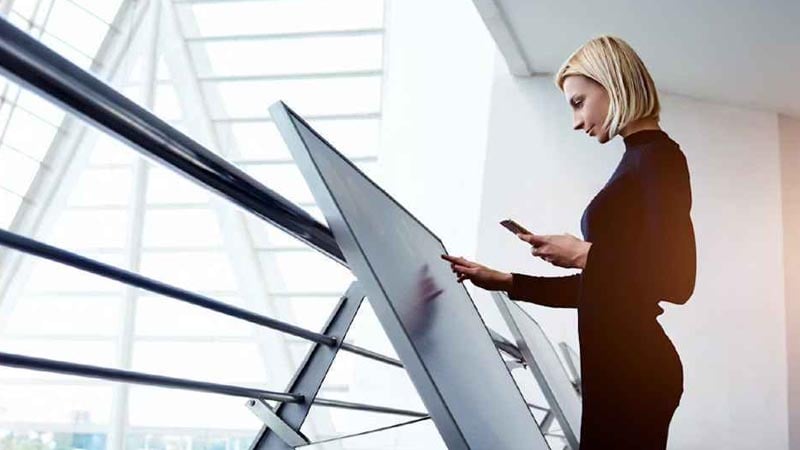 A female employee interact with wayfinding software on a large touch screen